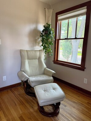 A room with a white leather chair and ottoman, a macrame wall hanging, and a window with a view of trees. - Luxury Farmhouse 2BD, 2BA & Office (Wheat Ridge)