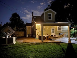 A house with a covered patio area, a hammock, and string lights.