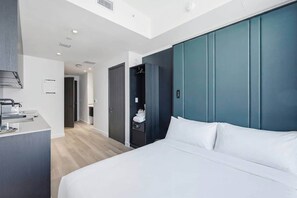 Habitació d'hotel moderna amb un llit gran, un armari encastat i una zona de cuina equipada.