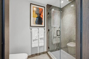 A modern bathroom with a glass-enclosed shower, a toilet, and a framed artwork on the wall. - Downtown Miami Studio at E11EVEN | 24th Floor (Miami)