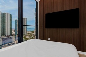 A hotel room with a large window, a bed, and a flat-screen TV mounted on a wooden wall. - E11EVEN Skyline Studio | 33rd Floor City Views (Miami)