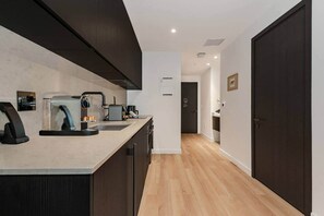 A modern kitchen with dark cabinetry, a countertop coffee machine, and a sink. - E11EVEN Skyline Studio | 33rd Floor City Views (Miami)
