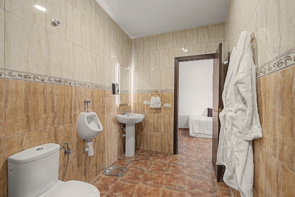 Ein Badezimmer mit Toilette, Urinal, Waschbecken und Handtuchhalter.