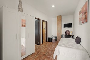 Ein Hotelzimmer mit Bett, Schreibtisch, Stuhl, Fernseher und Kleiderschrank.