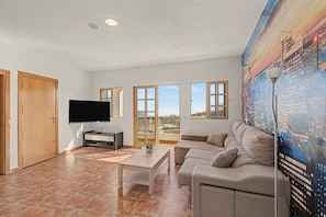 A living room with a flat-screen TV, a sofa, a coffee table, and a cityscape mural. - Vacation Apartment 'Apartamento Buen Lugar' with Sea View and Balcony (Buenlugar)