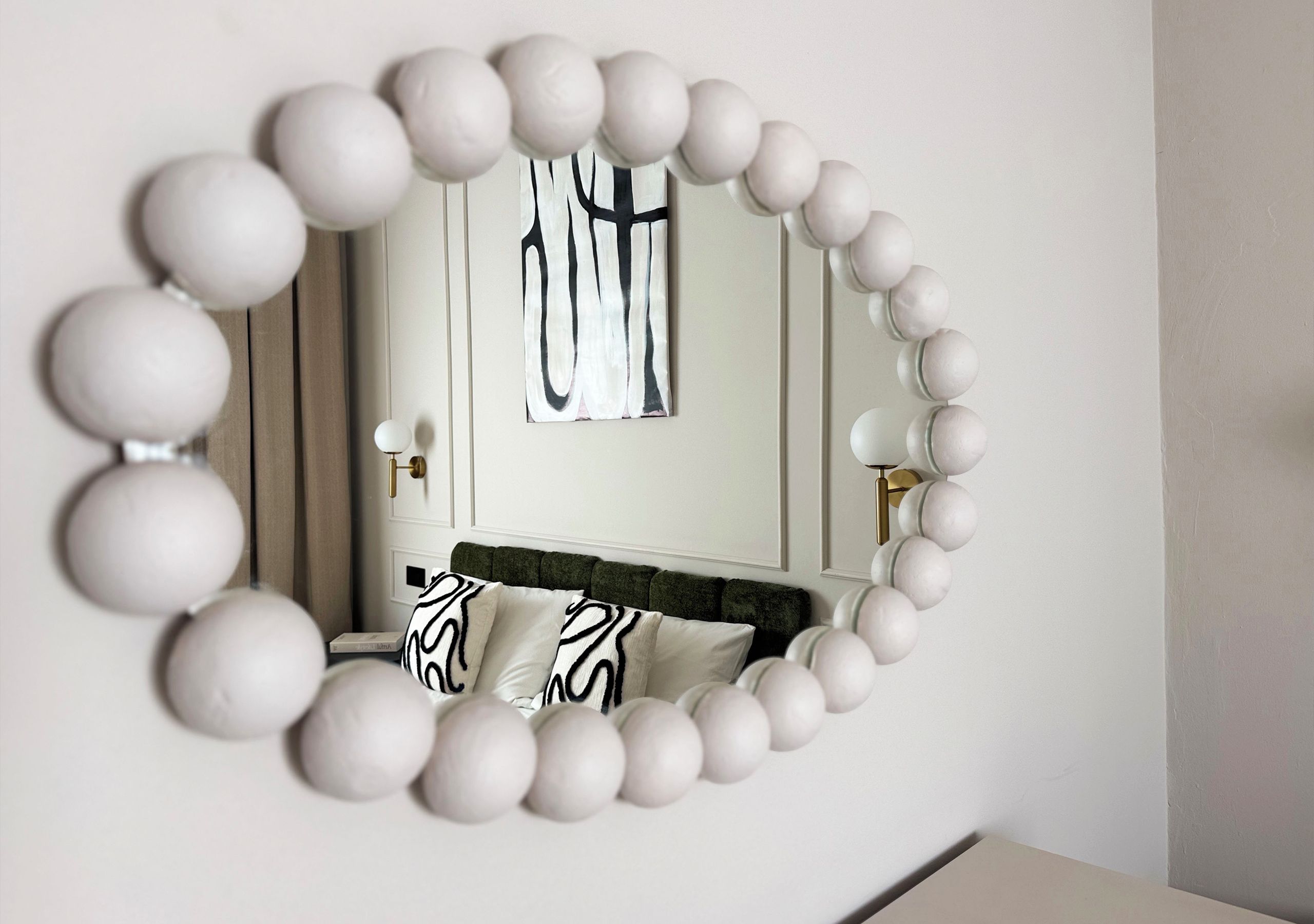 Ein Spiegel mit weißem Rahmen und ein Bett mit Kissen in ZEBRA-MUSTER.