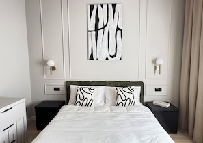 A hotel room with a bed, two bedside tables, a nightstand, a wall-mounted artwork, and a window with curtains. - Sander Homes | Malpensa Airport (MXP) 15 min | Milan 30 min (Busto Arsizio)