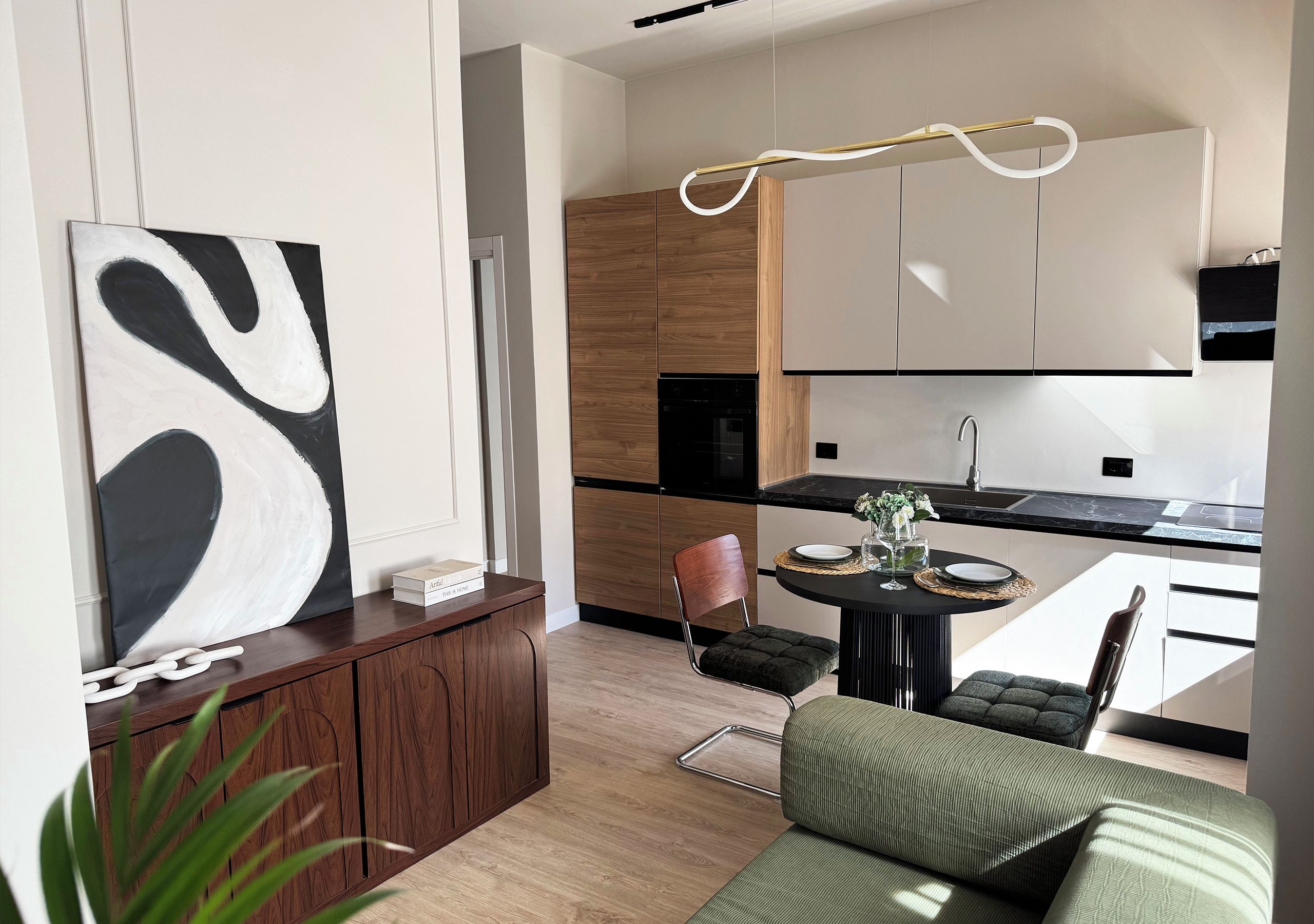 A modern kitchen with wooden cabinets, a black countertop, and a dining area with a round table and chairs.