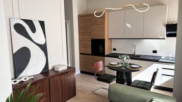 A modern kitchen with wooden cabinets, a black countertop, and a dining area with a round table and chairs.