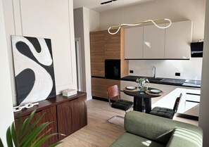A modern kitchen with wooden cabinets, a black countertop, and a dining area with a round table and chairs.