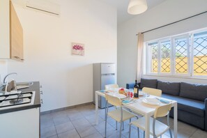 A modern kitchen with a built-in oven and a dining area with a table set for two. - Residence La Baia - Bilo PT by BarbarHouse (Casalabate)