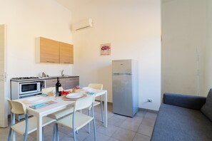 Eine kleine Küche mit Essbereich, einem Kühlschrank und einer Couch.