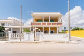 A two-story building with a gated entrance, a balcony, and a clear sky. - Residence La Baia - Bilo PT veranda by BarbarHouse (Casalabate)