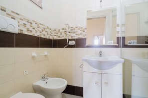 Casa de banho com sanita, bidé e lavatório.