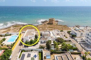 Uma área residencial à beira-mar, com torre, piscina e painéis solares.
