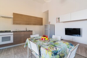 Eine moderne Küche mit Holzausstattung, einem eingebauten Backofen und einer Essecke mit Tisch für zwei Personen.