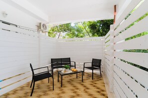 Un patio couvert avec une table et des chaises, une plante en pot et un livre.