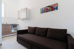 Um espaço de estar moderno com um sofá marrom, um micro-ondas e um armário na área da cozinha.