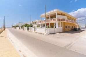 A multi-story building with a flat roof, a gated entrance, and a clear sky. - Residence La Baia-Trilo PP Standard by BarbarHouse (Casalabate)