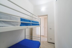 A bunk bed with a blue mattress in a room with white walls and a door in the background. - Residence La Baia-Trilo PP Standard by BarbarHouse (Casalabate)