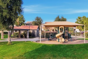 Un parc infantil amb tobogan i zona de seients coberta.