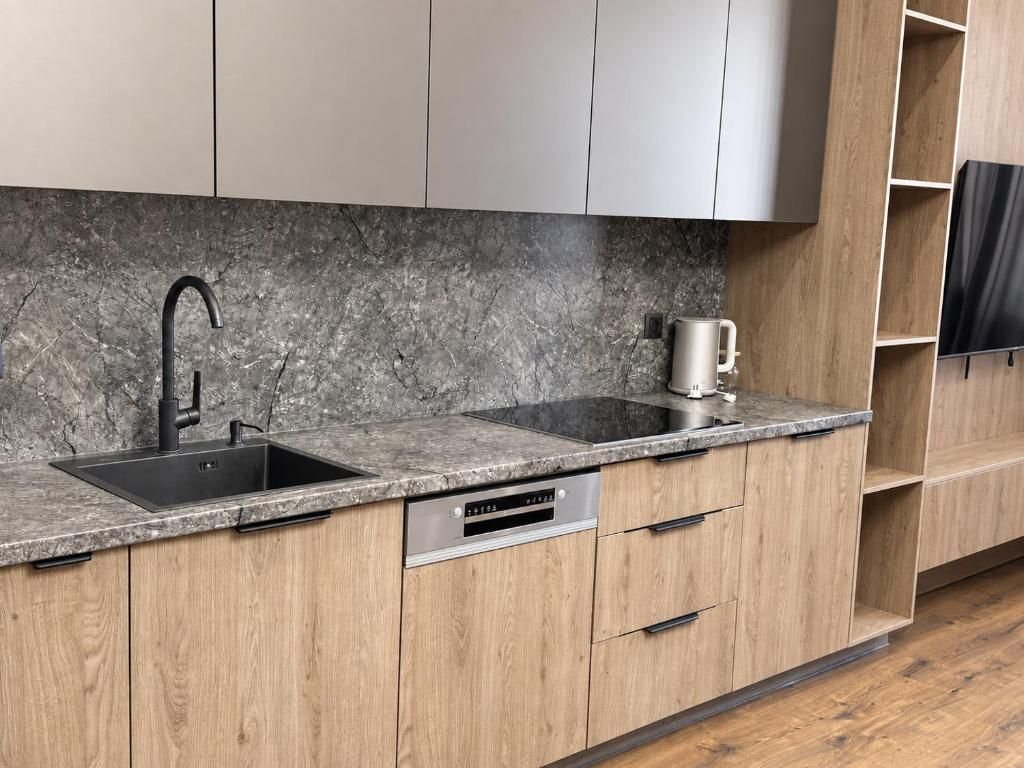 A kitchen with a granite countertop, stainless steel sink, and wooden cabinets.