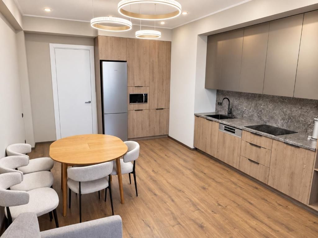 Une cuisine moderne avec des meubles en bois, un four encastré et un évier en acier inoxydable.
