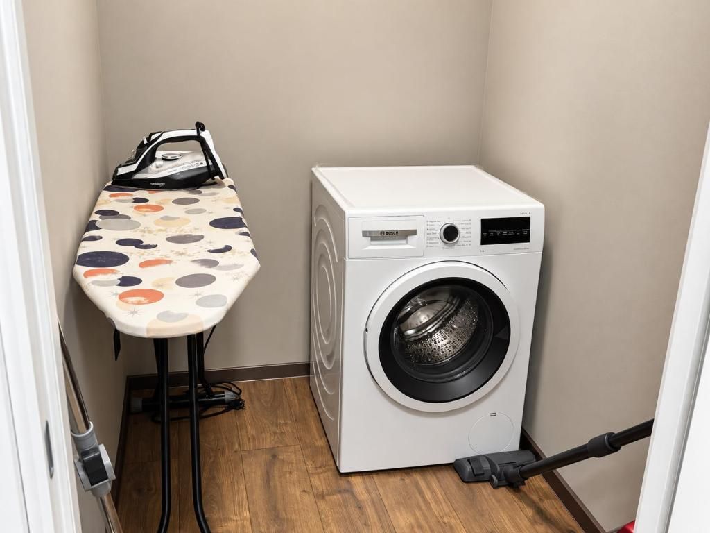 A compact laundry room with a washing machine and an ironing board.