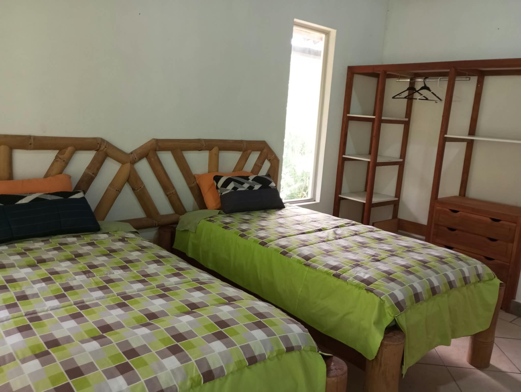 A room with two beds, a wooden wardrobe, and a window.
