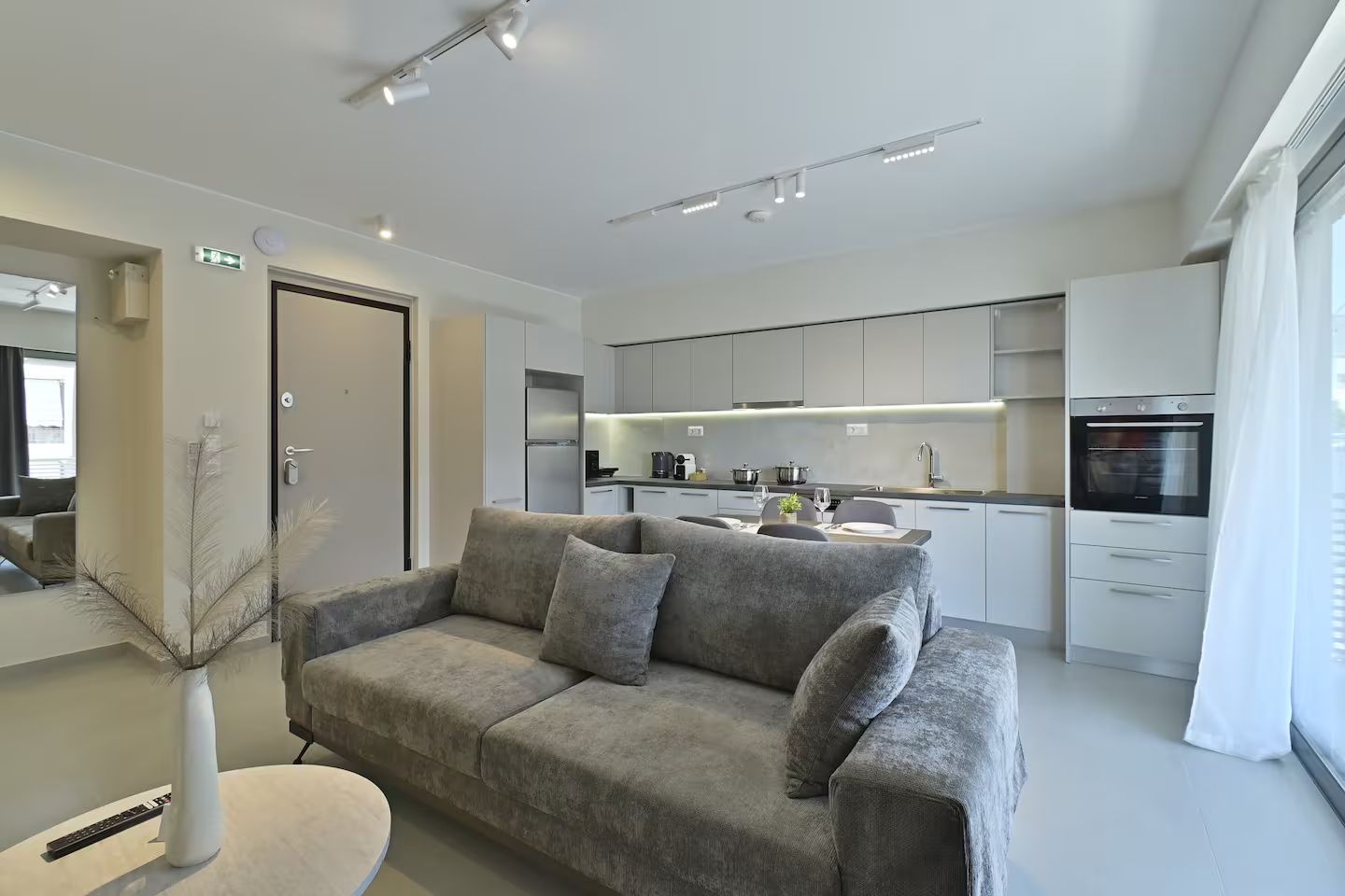 A modern living room with a grey sofa, a small round table, and a white vase.