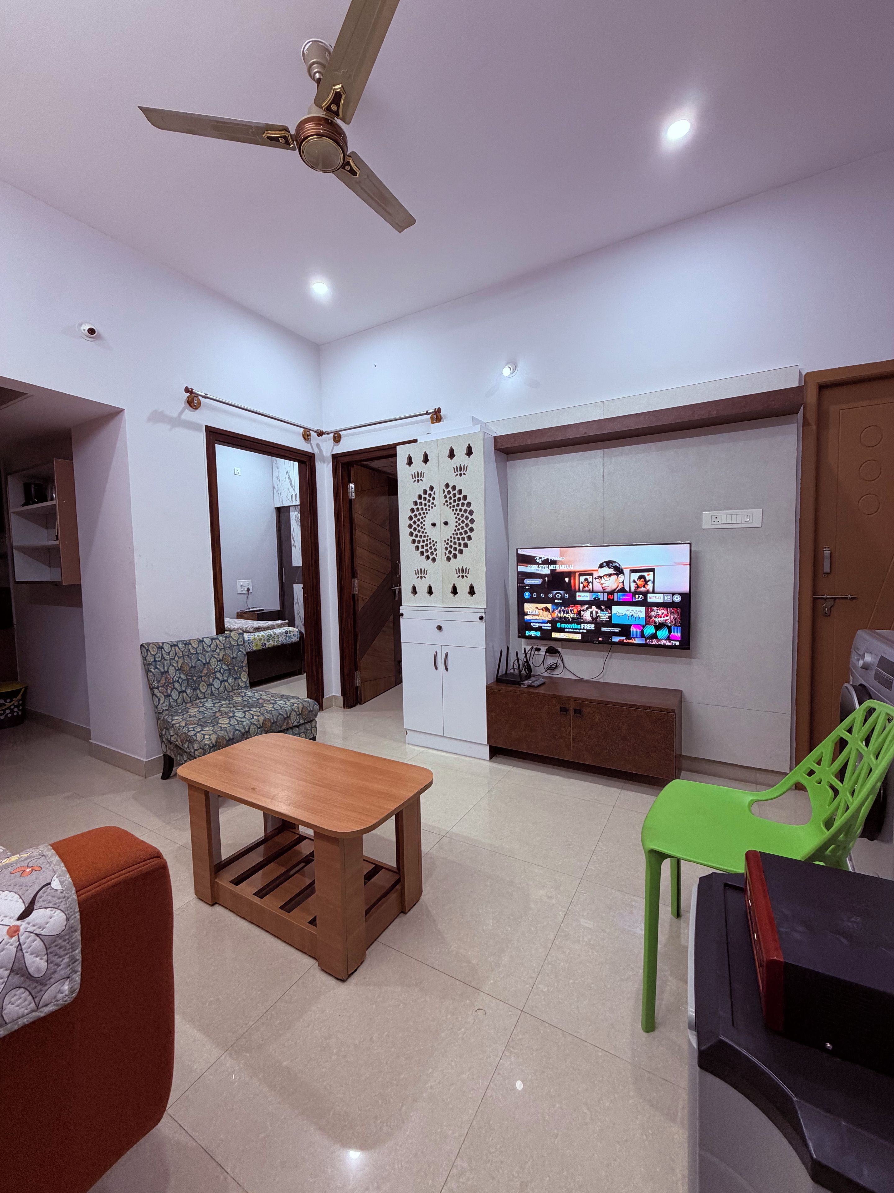 A living room with a sofa, a wooden coffee table, a television, and a ceiling fan.