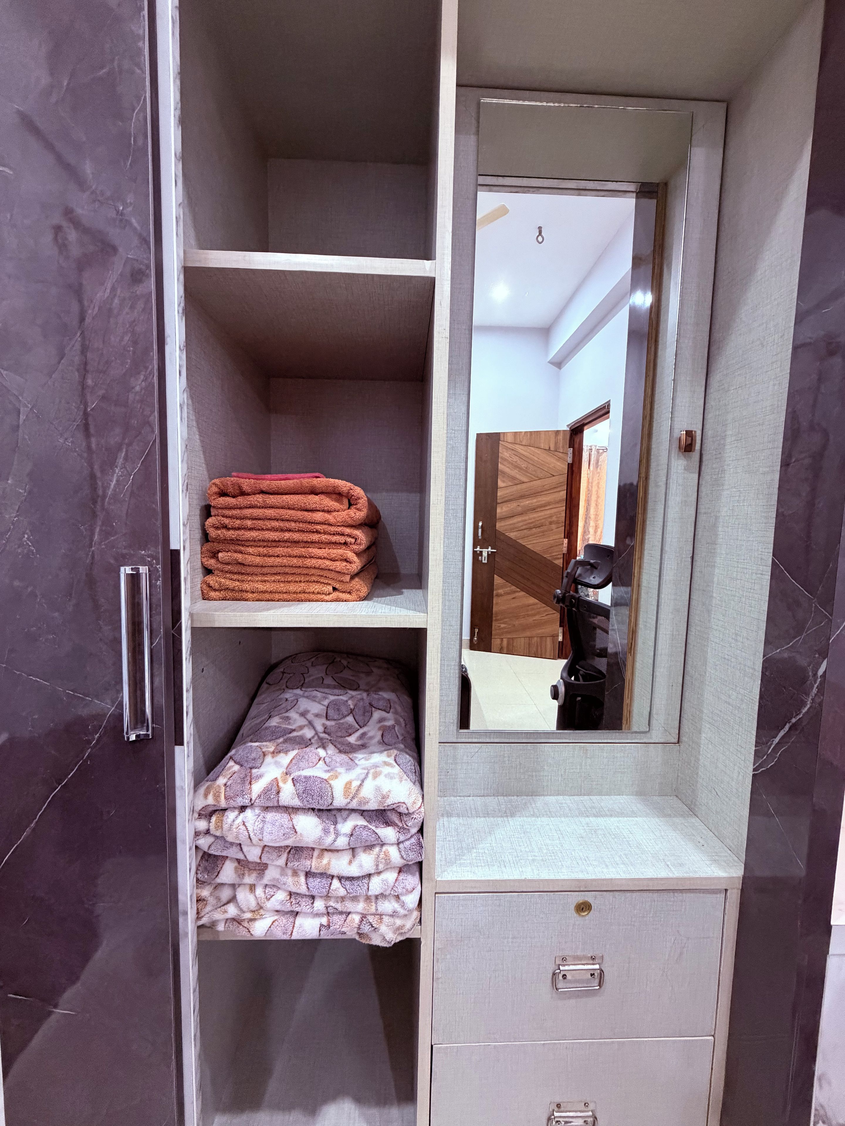 A wardrobe with a mirror, shelves, and drawers.