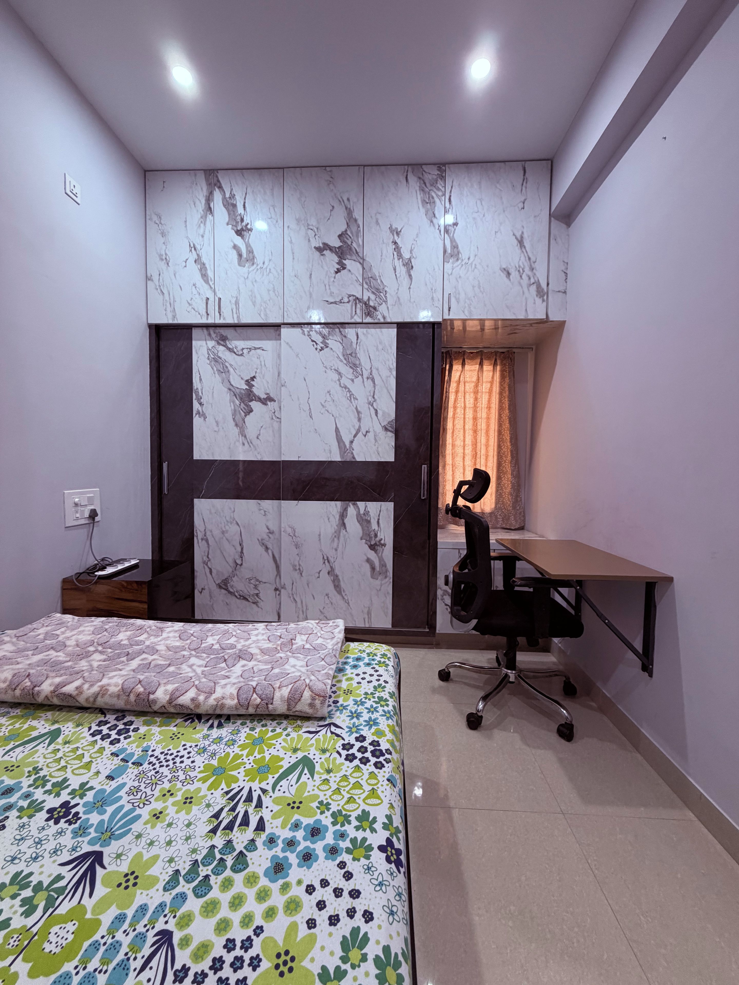 Ein Schlafzimmer mit einem Bett, einem Schreibtisch und einer Garderobe mit Marmorverkleidung.