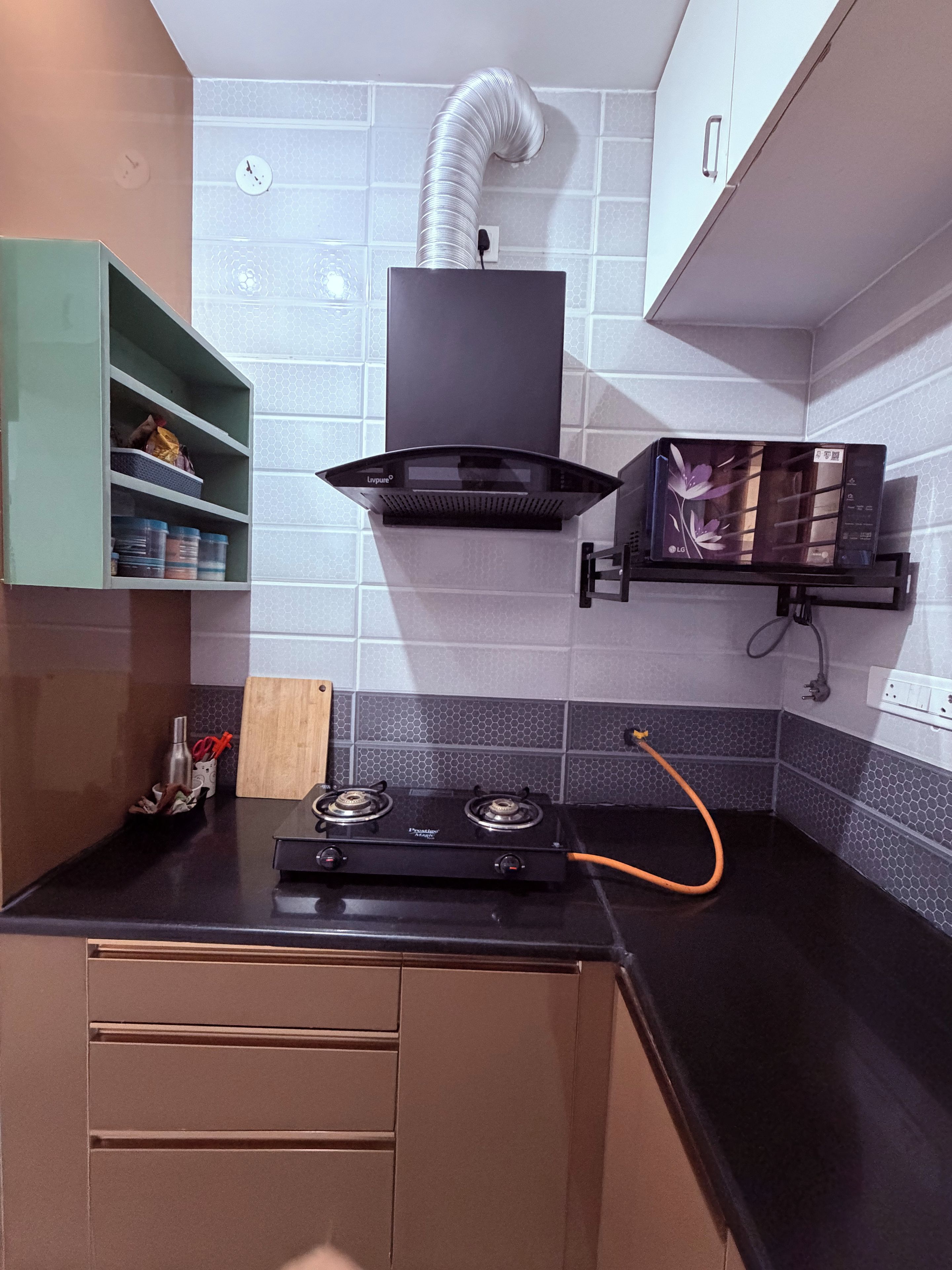 A kitchen with a gas stove, a range hood, and a microwave on a black countertop.