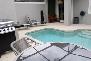 A pool area with a grill, lounge chairs, and a table. - Storey Lake 5BR Themed Rooms & Private Pool (Kissimmee)