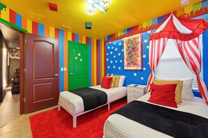 A room with a bed, a nightstand, a red rug, a green door, and a wall with a colorful pattern. - 5BR Disney-area Home Pool, Theater, Themed (Kissimmee)