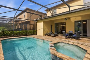 A pool area with a glass-enclosed patio, lounge chairs, and a table. - 5BR Disney-area Home Pool, Theater, Themed (Kissimmee)