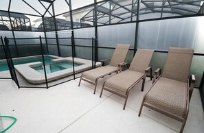 A covered outdoor area with a pool and lounge chairs. - Themed 5BR Near Disney Pool, Game Room (Kissimmee)
