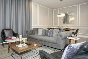 Ein modernes Wohnzimmer mit einem grauen Sofa, einem Couchtisch und einem Essbereich mit einem Kronleuchter.
