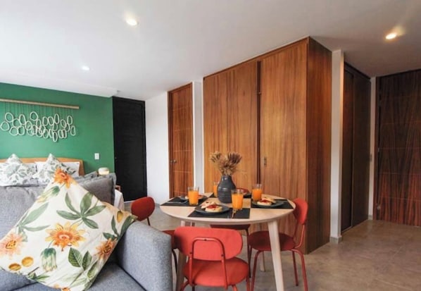 A dining area with a round table, red chairs, and a green wall with a decorative pattern. - Excellent hotel in downtown Guadalajara (Guadalajara)