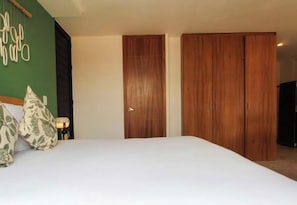 A bedroom with a bed, two wooden wardrobes, and a green wall with a decorative item. - Excellent hotel in downtown Guadalajara (Guadalajara)