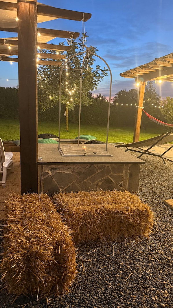 An outdoor patio area with a pergola, string lights, and a seating arrangement.