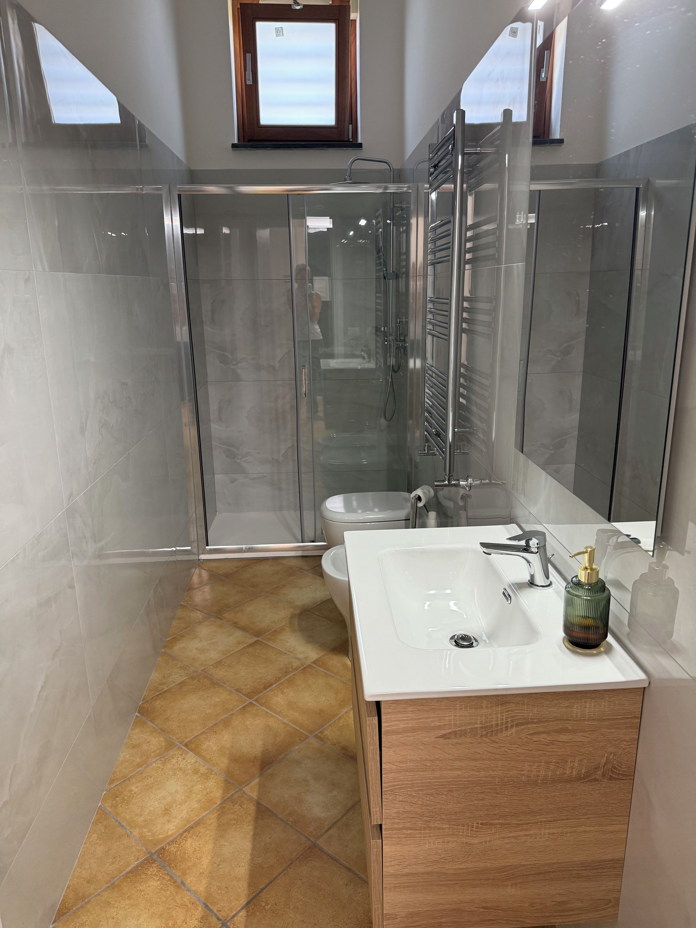Ein modernes Badezimmer mit einer gläsernen Dusche, einem weißen Waschbecken und einem Holzkosmetikschrank.