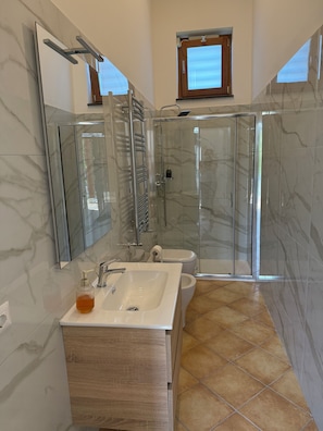 A bathroom with a glass-enclosed shower, a sink with a soap dispenser, and a toilet. - Residenza Don Alfonso (Somma Vesuviana)