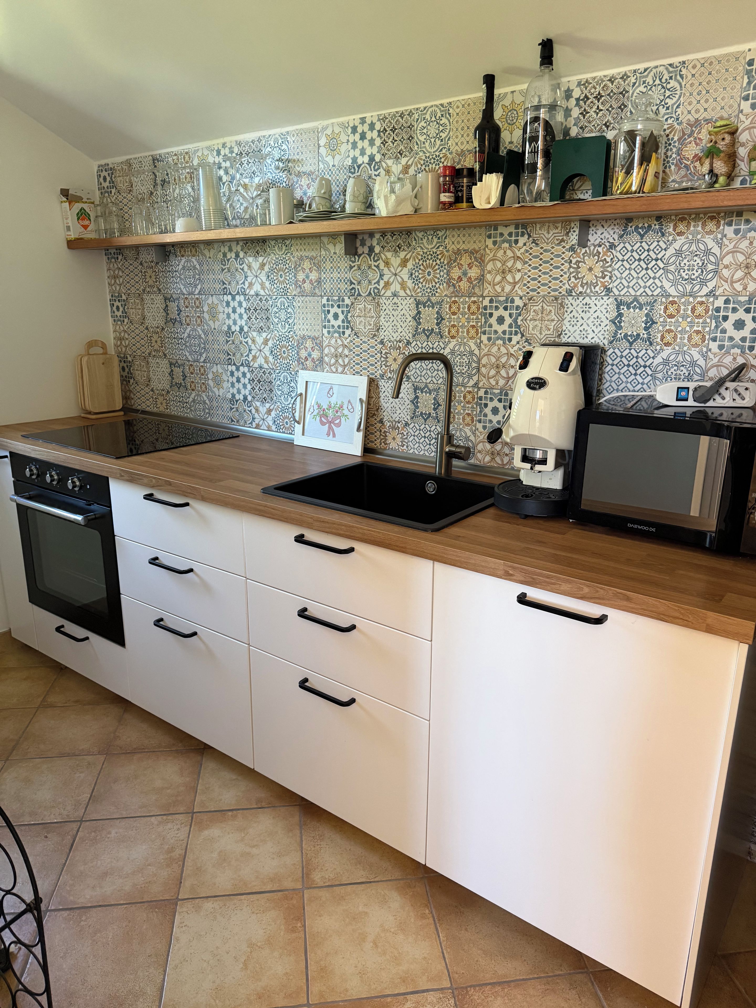 Una cocina equipada con horno empotrado, lavavajillas, pileta y cafetera.