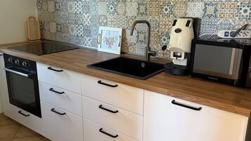 Una cocina equipada con horno empotrado, lavavajillas, pileta y cafetera.