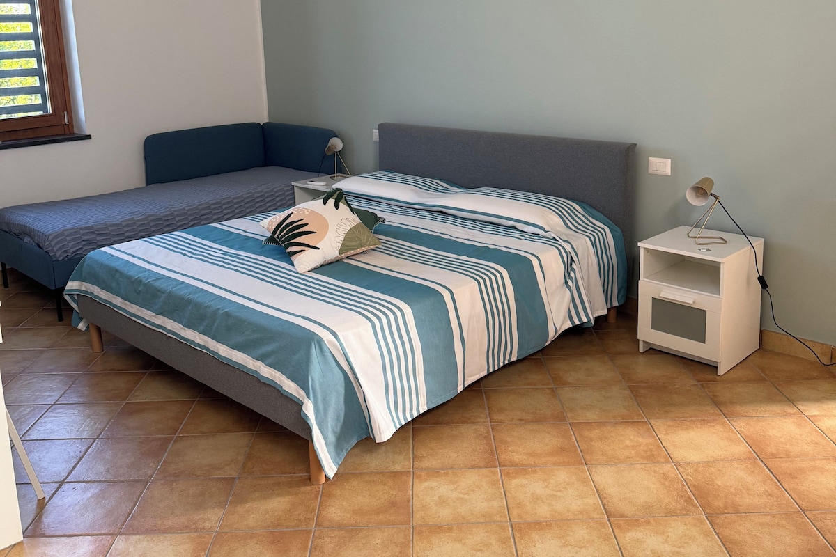 A bedroom with a bed, a nightstand, and a window.