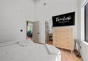 A bedroom with a bed, a dresser, a television, and a window. - EV Charger | Hot Tub | Sleeps 16 | Games (Broken Bow)