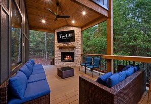 Ein überdachter Sitzbereich im Freien mit einem Kamin aus Stein, Korbmöbeln und einem Schild für TreeLine Vacation Rentals.