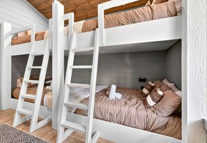 Een slaapkamer met een stapelbed, witte leuningen, een ladder en een grijze wand.